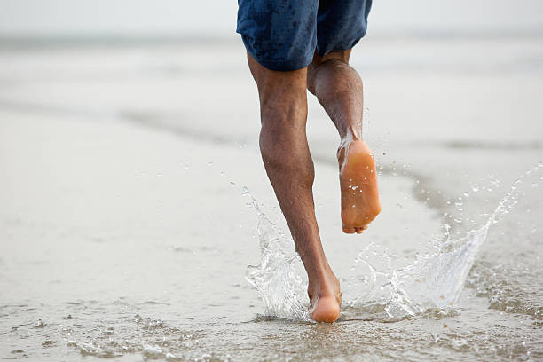 a piedi nudi uomo in esecuzione in acqua - barefoot foto e immagini stock
