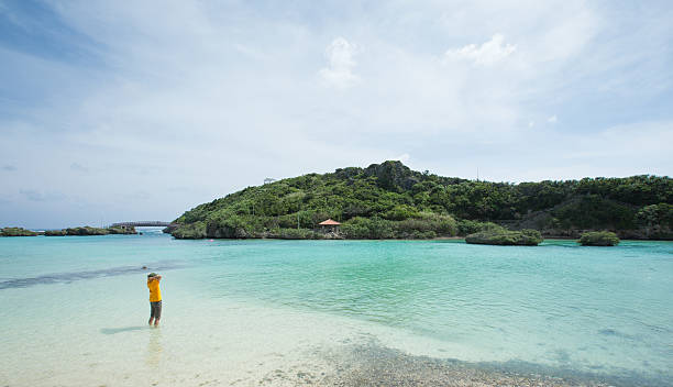 Man standing in idyllic tropical lagoon of Okinawa Man in yellow t-shirt standing in a beautiful tropical lagoon on Miyako-jima, Okinawa, Japan white beach okinawa stock pictures, royalty-free photos & images