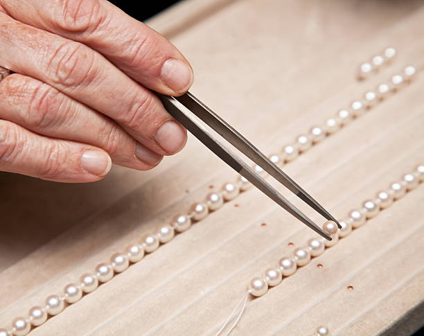 Close hand jeweler stringing pearls
