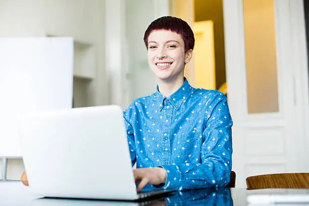Portrait of young woman working at startup looking happy