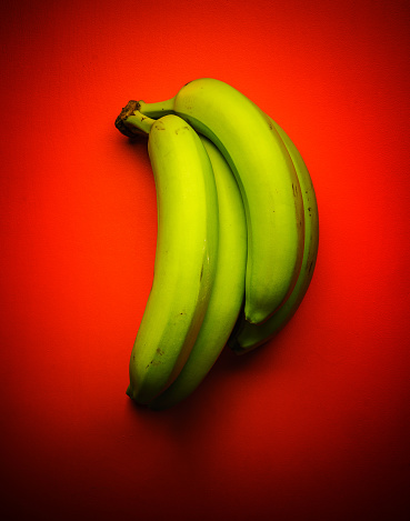 Green banana bunch on red background