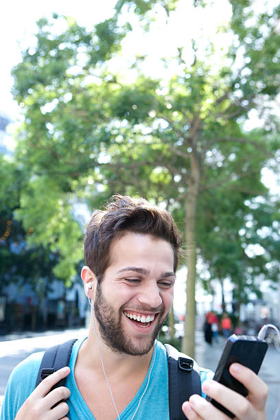 istock Young man smiling with backpack and looking at mobile phone 522360735