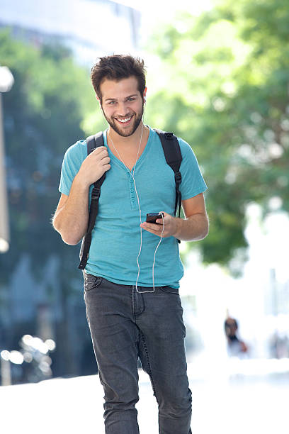 istock Young man walking outdoors with bag and mobile phone 522360951