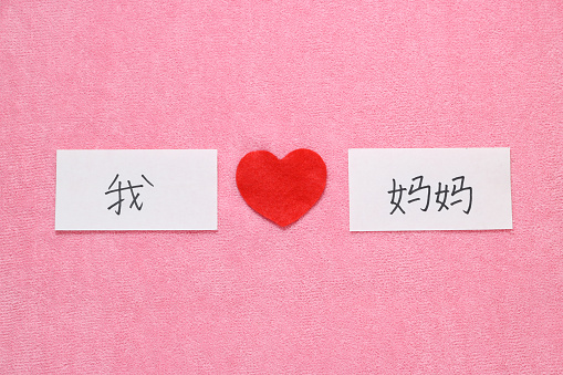 Red heart and hand written letters spelling I Love mom concept in Chinese.