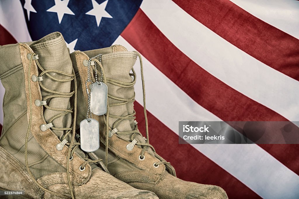 Old combat boots and dog tags with American flag Old combat boots and dog tags with American flag in the background. Vintage filter effects. Dog Tag Stock Photo