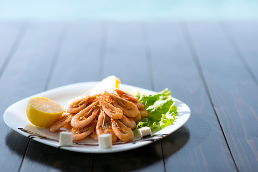 Grilled Shrimps with Spices, Herbs and Lemon in a Plate by the Sea.