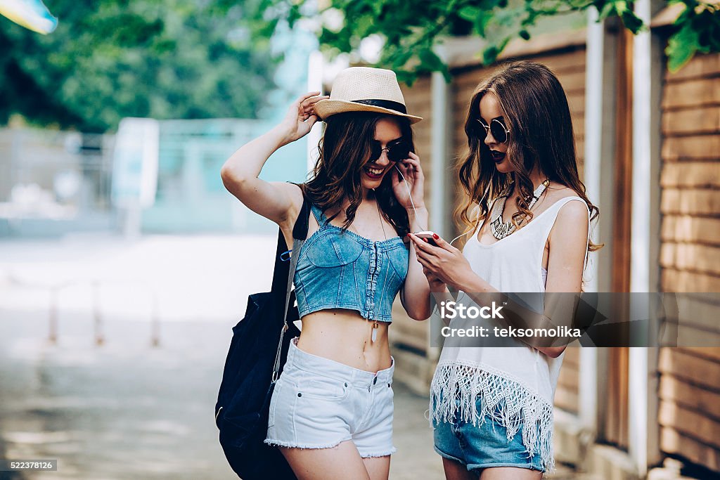 Two young beautiful girls Two young beautiful girls are walking through the city and listen to music Fashion Stock Photo