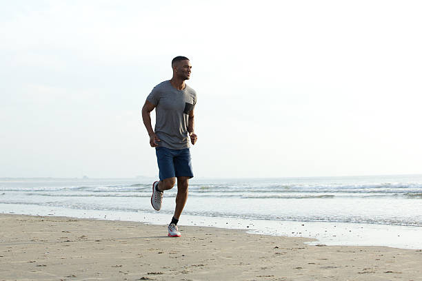 istock Young african man jogging at the beach 522378211