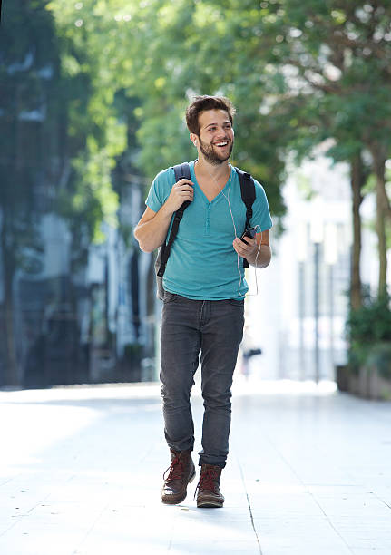 istock Cheerful young man walking with mobile phone and bag 522380771