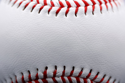 A close up of a baseball showing the texture of the leather ;  shot with very shallow depth of field