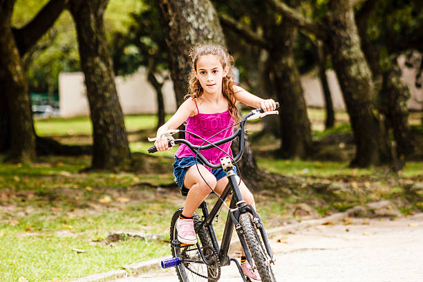 little girl riding a bike - brazil bicycle rio de janeiro outdoors fotografías e imágenes de stock