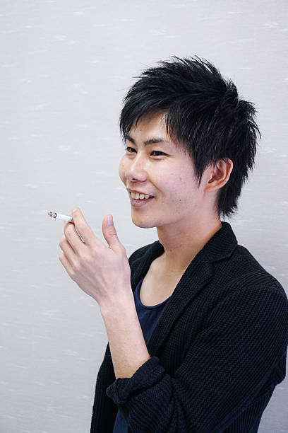 Young adult man smoking a cigarette agaisnt white background