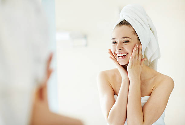 Facial care Happy girl looking at her face in mirror after bath body care stock pictures, royalty-free photos & images