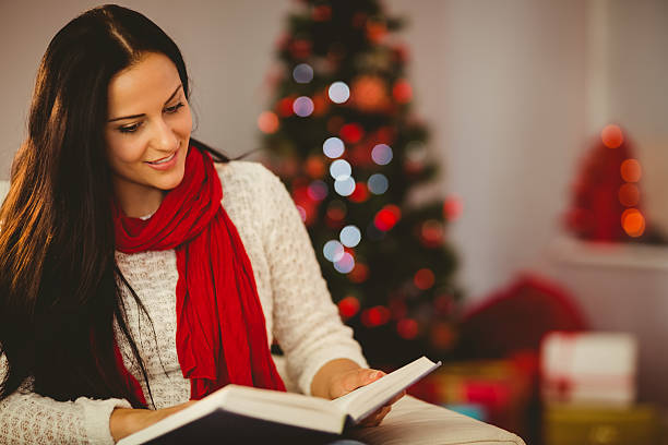 istock Pretty brunette reading on couch at christmas 522398293