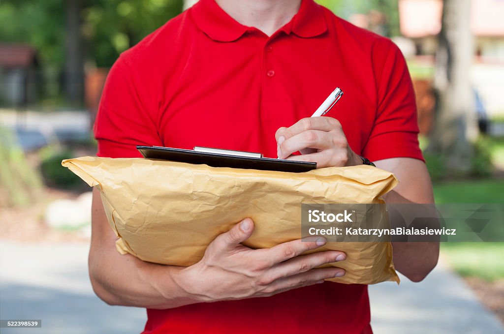 Delivery guy does his paperwork Delivery man filling in forms on parcel Carton Stock Photo