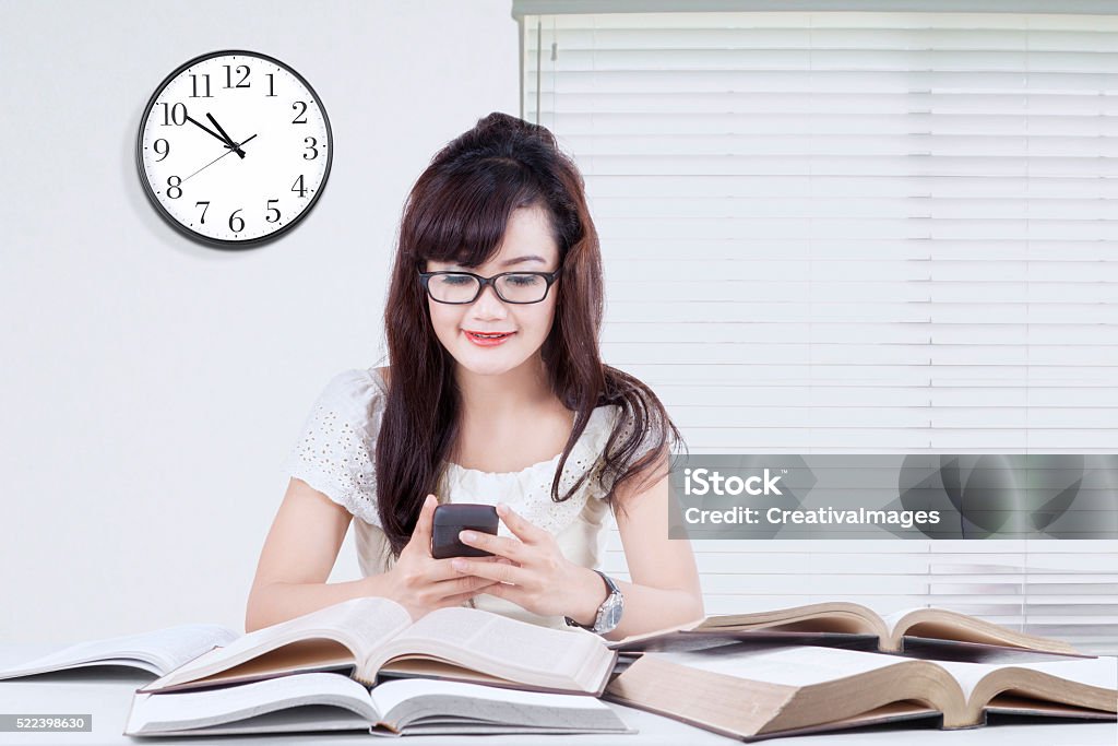 Using Mobile While Reading Student Using Cellphone While Studying Stock Photo - Download Image Now ...