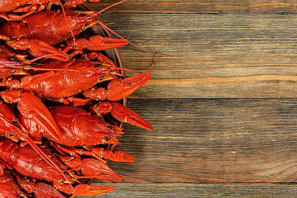 A dish with boiled crawfish on a wooden background