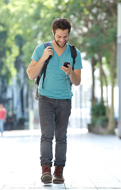 istock Smiling man walking with mobile phone and bag 522400207