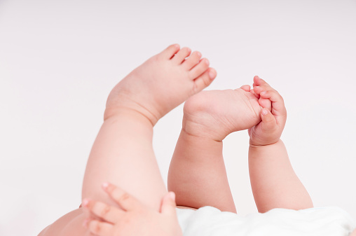 Close up of baby charming small legs on white background