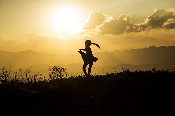istock Little Girl Playing with her Coat Silhouetted by Setting Sun 522404501