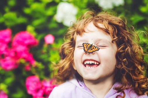 Laughing girl with a butterfly on his nose