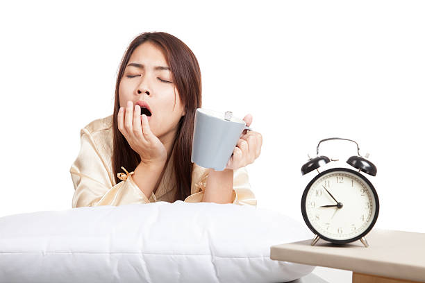 asiatica ragazza svegliarsi e sbadigliare con clock e tazza di caffè - yawning women drink coffee cup foto e immagini stock