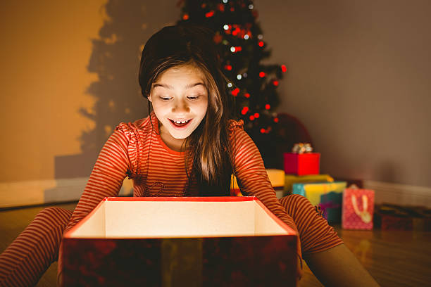 istock Little girl opening a glowing christmas gift 522419671
