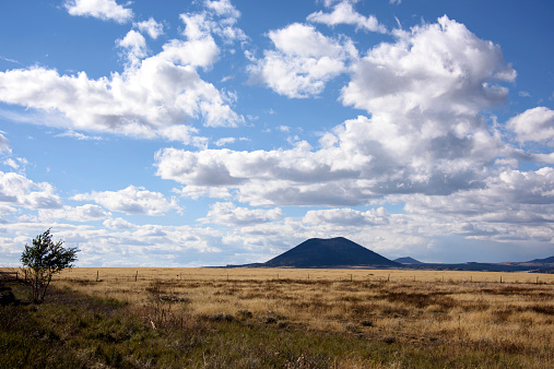 Landscape in New Mexico high desert in the American Great Plains, showing grassy prairie, with the extinct Capulin volcano in the distance.