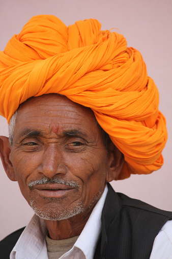 Pushkar, India, November 28, 2012: Senior Indian Man with orange turban. Image taken in the street, He is looking at the camera