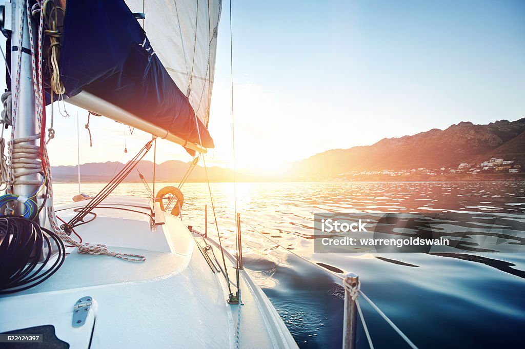 sailing ocean boat Sailing yacht boat on on ocean water at sunrise with flare and outdoor lifestyle Sailing Stock Photo