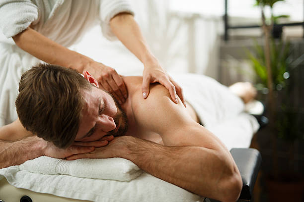 Back massage at the spa Young man relaxing in the spa and receiving back massage. man massage stock pictures, royalty-free photos & images