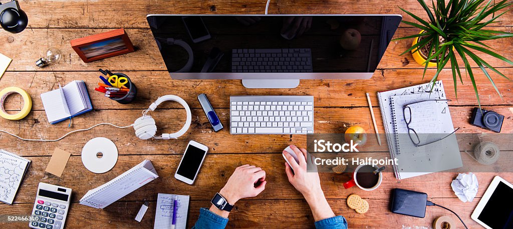 Business person working at office desk wearing smart watch Business person working at office desk. Smart watch on hand and smart phone on the table. Coffee cup, notepad and glasses and various office supplies around the workplace. Flat lay. Apple - Fruit Stock Photo