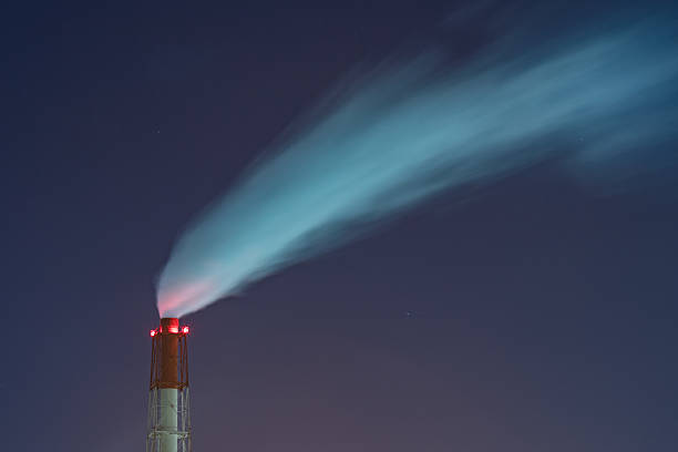 istock Large chimney spewing smoke at a factory at night 522467466