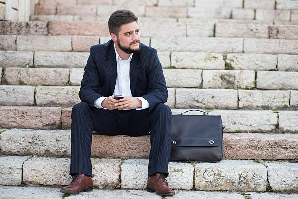 istock Young businessman using a phone sitting on the stairs 522468211