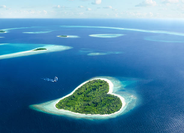 heart island in the maldivian tropical sea heart-shaped island in the tropical sea valentines day holiday stock pictures, royalty-free photos & images