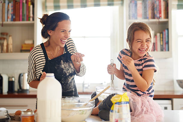 Flour and fun make for some delicious food! Shot of a little girl having fun baking with her mother in the kitchen throwing photos stock pictures, royalty-free photos & images