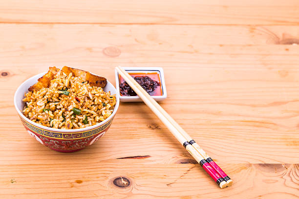a bowl of wok noodles and chopsticks isolated on blue background. Vertical image. Image contains copy space