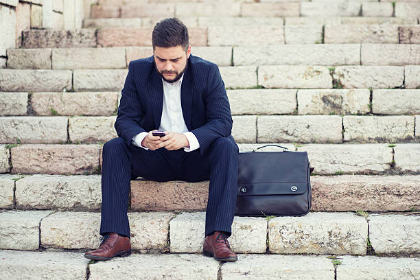 istock Young businessman using a phone sitting on the stairs 522471977