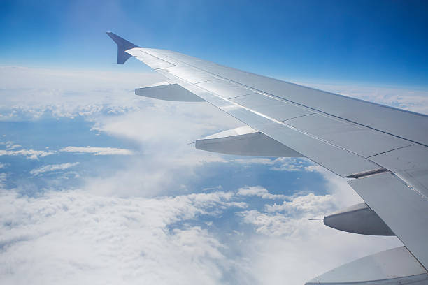 View through the window of a passenger plane flying above beautiful white clouds in to the sky