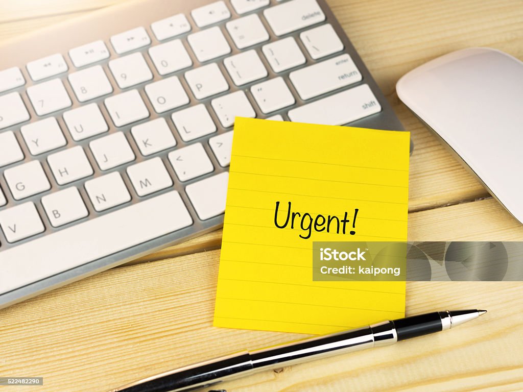 Urgent on sticky note on work table Activity Stock Photo