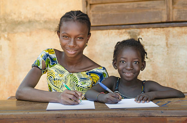 School For African Children - Couple Smiling Whilst Learning Couple of cute African children sitting in their desk at school in Bamako, Mali.  africa school stock pictures, royalty-free photos & images