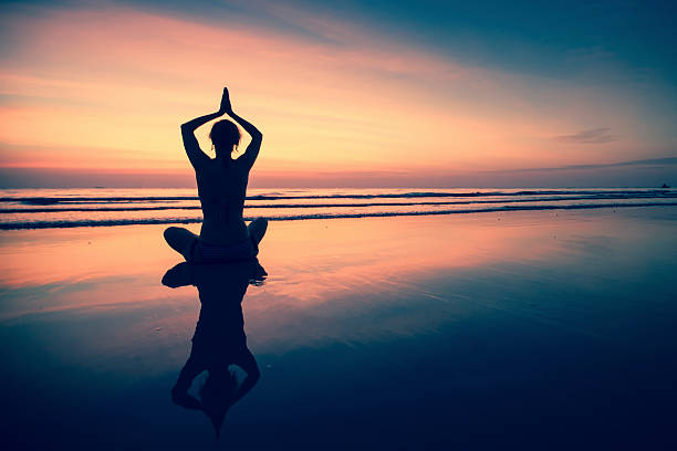 istock Silhouette young woman practicing yoga on beach at surrealistic sunset. 522488759