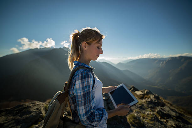 istock Woman at top of mountain using digital tablet 522489847