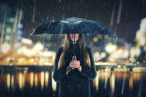 istock Woman under rain with black umbrella 522508519