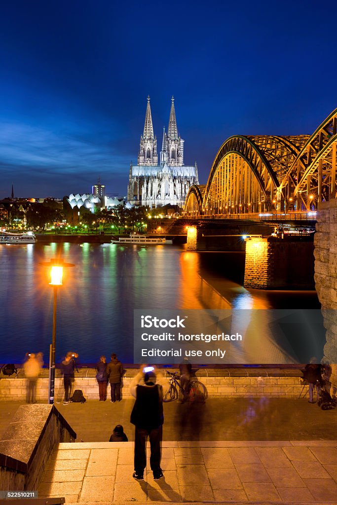 Cologne Cathedral, Germany Cologne, Germany - November 08, 2014. The illuminated Cologne Cathedral (Kölner Dom) and Hohenzollern Bridge at night. The cathedral is Northern Europes largest gothic church. View from the opposite side of the River Rhine. The small square at the end of the Hohenzollern Bridge is highly frequented by tourists enjoying the majestic Cathedral. Ancient Stock Photo