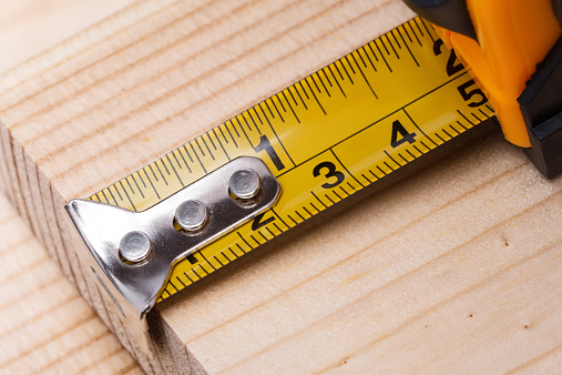 Yellow steel tape measure on wooden plank. Repair and building concept