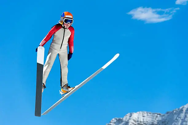Front view of young male ski jumper during the ski jump against the blue sky