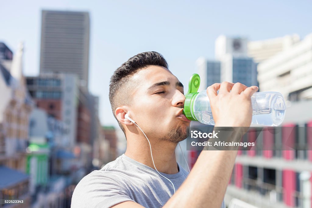 athlete drinking water from his bottle african athlete closing his eyes as he sips from his water bottle after his run in the city. cape town, western cape, south africa Africa Stock Photo