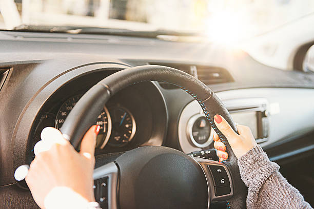 donna che tiene il volante e guida auto durante il giorno - car steering wheel windshield speedometer foto e immagini stock