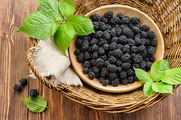 Blackberry in wooden bowl in basket stock photo